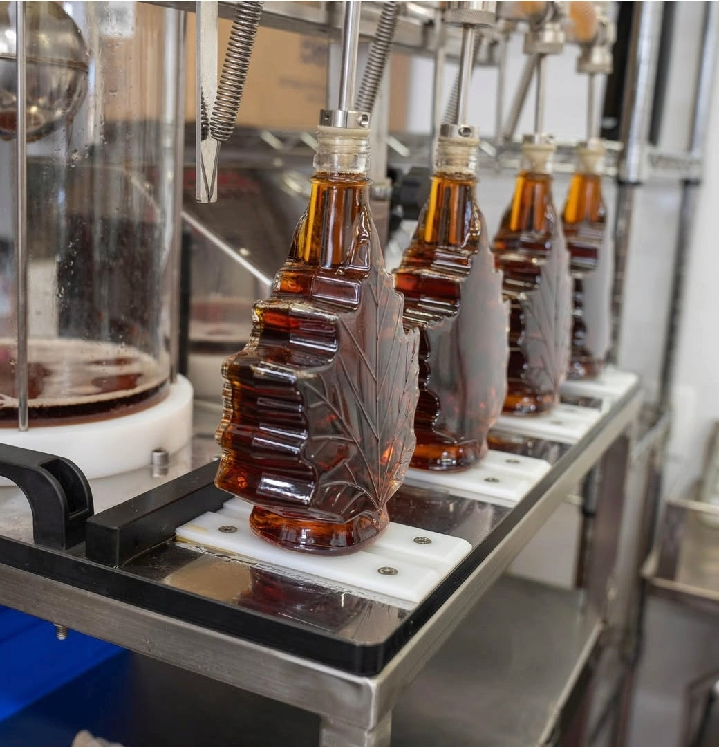 Bottles of autumn leaf glass maple syrup bottles in CFIA certified canning facility