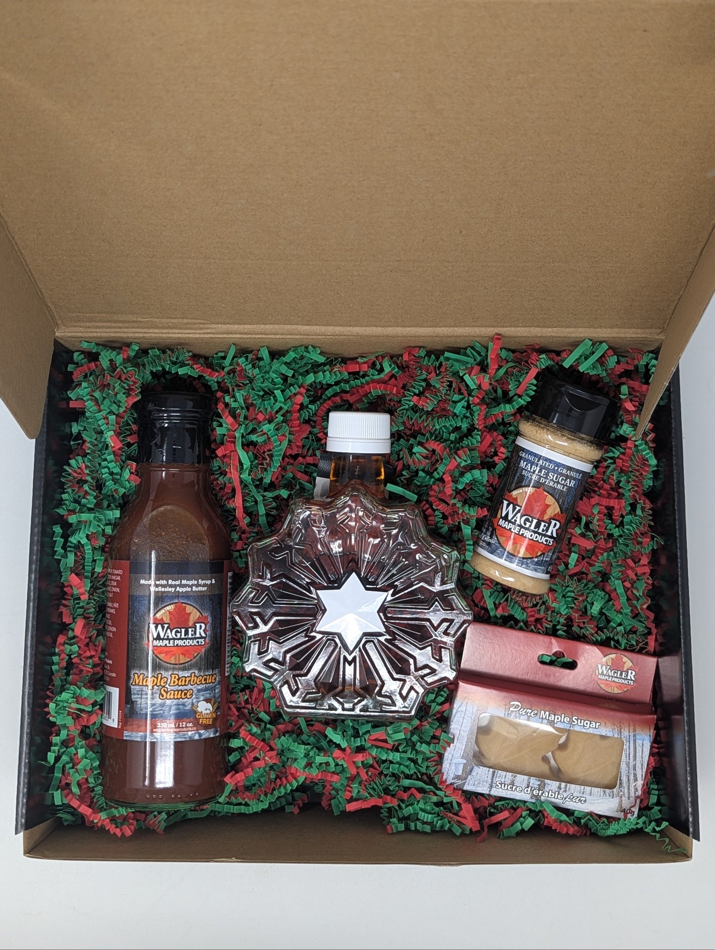 Gift box with holiday themed items including snowflake, BBQ sauce, maple sugar, and maple sugar candies