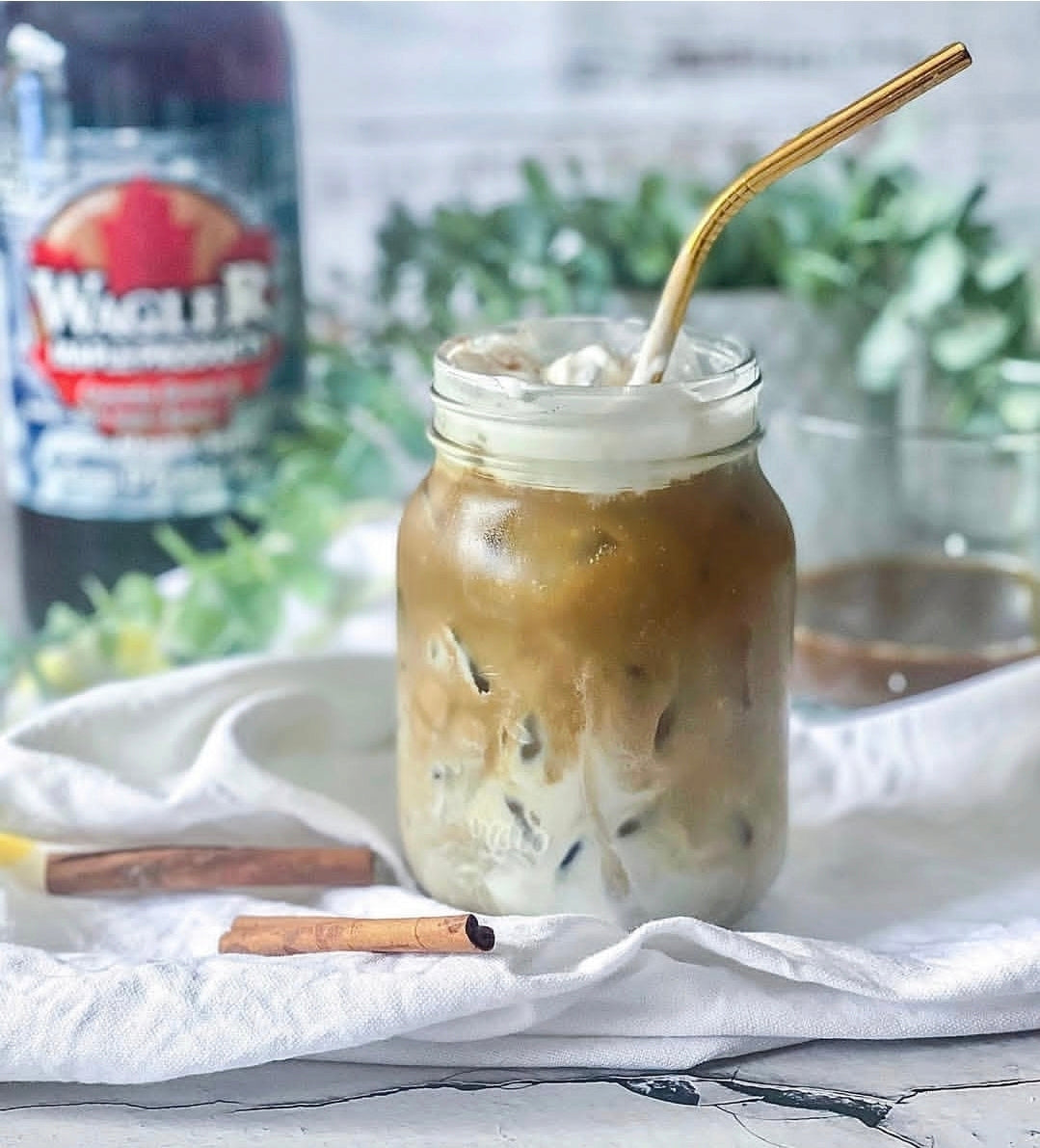 Mason jar of iced coffee with a straw and a Wagler Maple Products pure Ontario maple syrup in the background